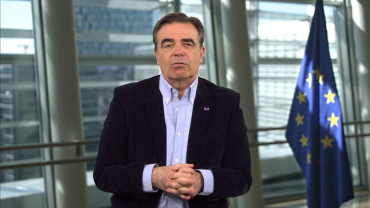 Man speaking to camera, with the EU flag in the background